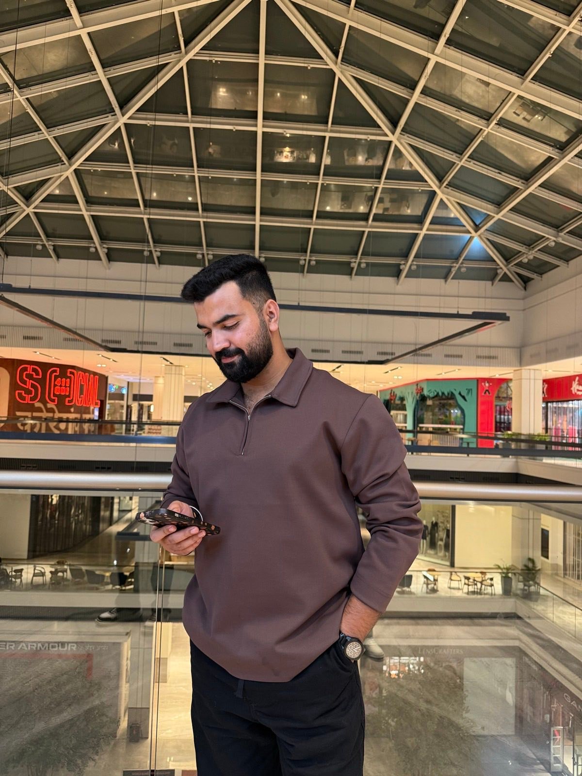 Rishav checking his phone in a glass atrium